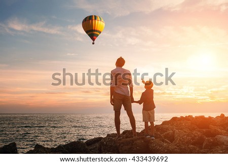 Father with son look on the balloon on the sea coast