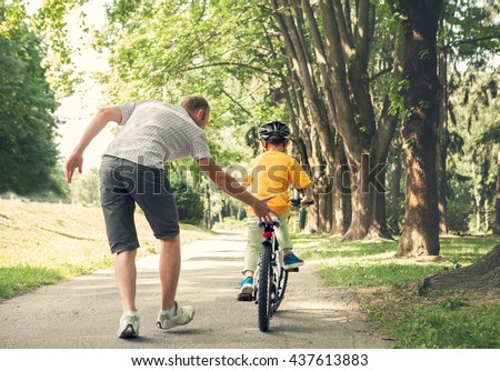 Father learn his little son to ride a bicycle