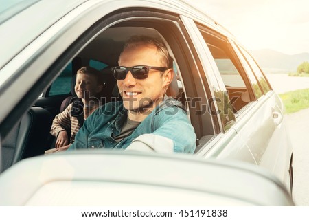 Father and son look out from car window