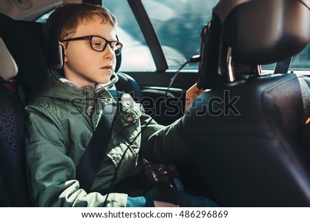 Boy watch a tablet on the car back seat