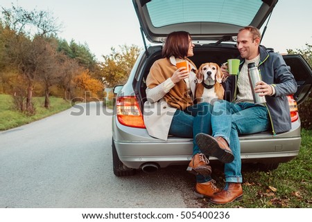 Tea party in car trunk - loving couple with dog sit in car trunk