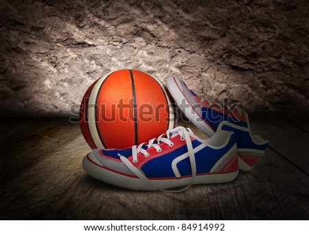 The pair of sport shoes and basketball ball on the wooden floor
