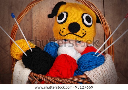 Boy in funny animal knitting hat with basket of color yarn