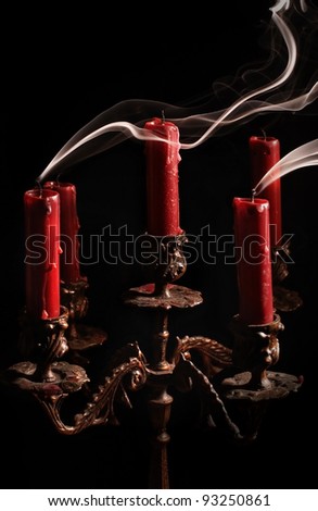 Blown candle with line of smoke in massive bronze candlestick