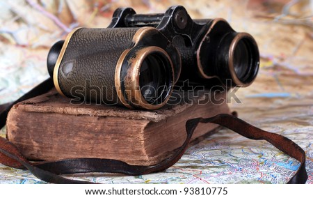 Vintage binocular with antique book at the topographic map background