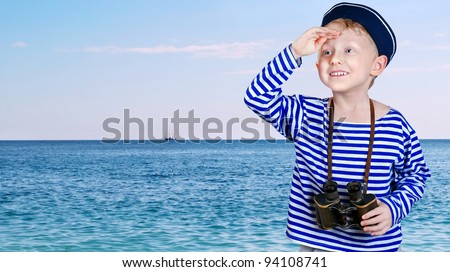 Little boy in sailor\'s uniform with binocular looks into the distance from the arm at the sea view background