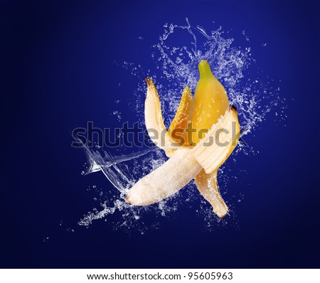 Yellow banana with the peeled  skin  in water splashes on the dark blue background