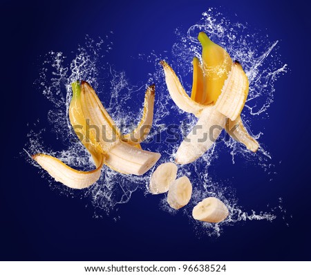 Two Yellow bananas with the peeled  skin  in water splashes on the dark blue background