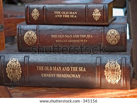 Three stacked leather bound books by Ernest Hemingway.