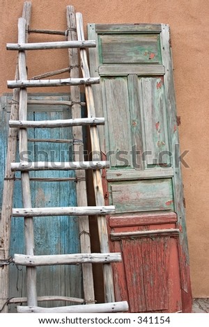 Old wooden ladder and doors against a wall in  a courtyard in Santa Fe, NM.