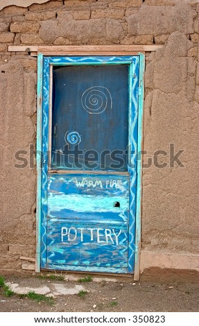 Blue door in an adobe wall leading to a traditional pottery shop in a pueblo in northern New Mexico.