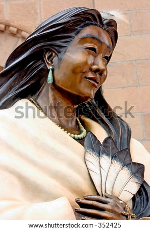 Bronze statue of an Indian woman holding four feathers at a church in Santa Fe, NM.