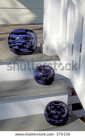 Blue glass vases on gray and white porch steps of an art gallery in Lenox, MA.