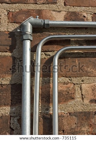 Three electrical conduits attached to a brick wall.