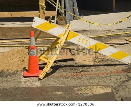 Orange safety cone and yellow striped construction barrier.