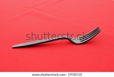Plastic fork on a red table cloth.