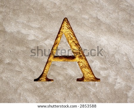 An upper case letter A chiseled into a piece of granite and inlaid with gold paint.