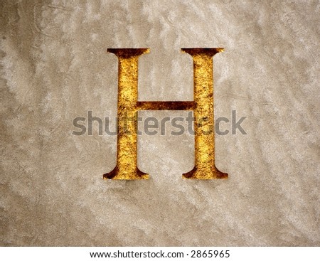 The letter H chiseled into a block of granite and embossed with gold paint.