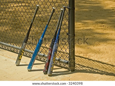 Baseball bats leaning against a fence at a ball field in Central Park New York City.