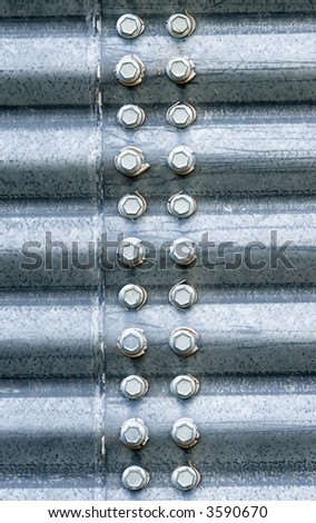 Hex-head bolts connecting two corrugated steel panels of a grain storage silo.