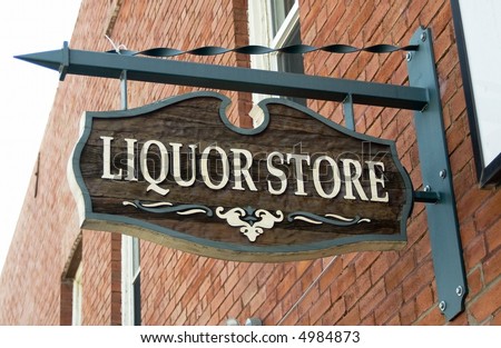 Liquor store sign hanging on a red brick wall.