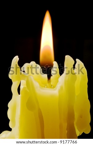 Close-up of a lighted yellow wax candle.