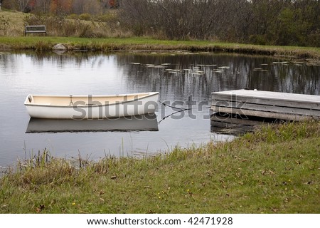 Rowboat tied to a dock and floating in a pond in Bar Harbor Maine.