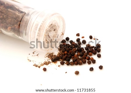 Fresh ground black peppercorns on a plate isolated on white background