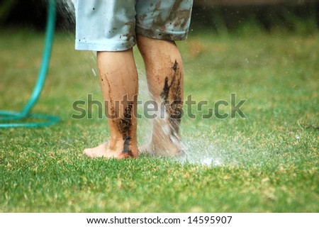Two feet of a caucasian white child playing in the mud with water in the backyard outdoors