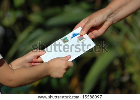 A little white hand of a caucasian girl toddler receiving a letter from her grandmother in the garden during sunset