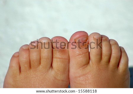 Little white feet with dirty and wet toes of a caucasian child in summertime