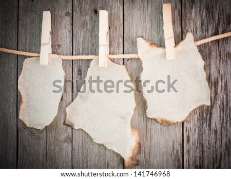 old burnt paper attach to rope with clothes pins on wooden background