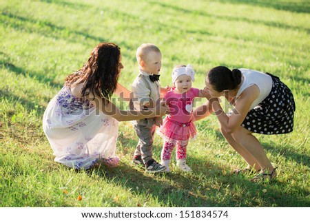 two mothers with children in summer park