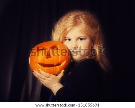 little witch with pumpkin on dark background