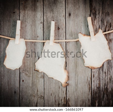 old burnt paper attach to rope with clothes pins on wooden background