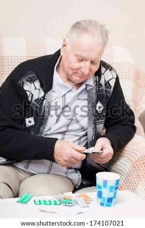 old men holding a medicine pill at home