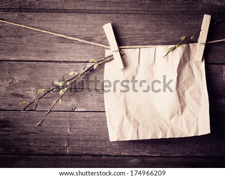 paper attach to rope with clothes pins and branch of willow on wooden background