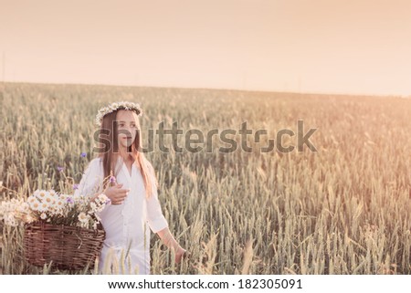girl in the wheat field with basket of flowers