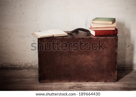 Vintage old  suitcase with old books on floor