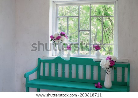 green bench at window and flowers in vases