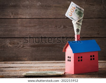 Dollars banknotes falling in house on wooden background