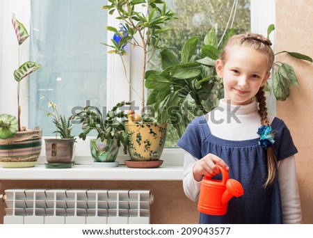 happy girl watering potted plant at home
