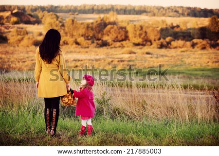 mother and daughter walking in autumnal field