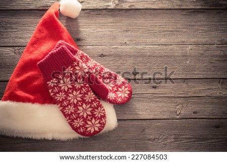 Santa\'s hat and red mitten on old wooden background