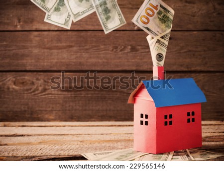 Dollars banknotes falling from  house on wooden background