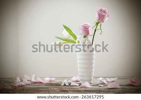 pink roses in broken flower vase on old wooden table