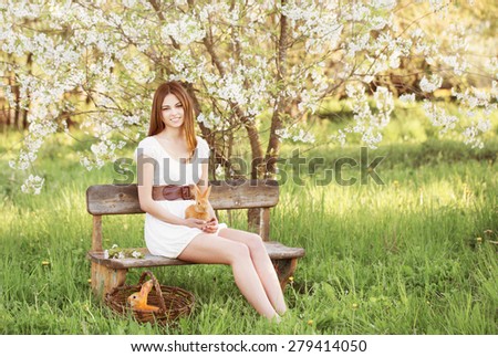 beautiful young woman with rabbits in garden