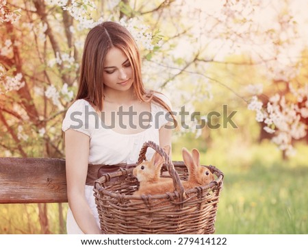 beautiful young woman with rabbits in garden