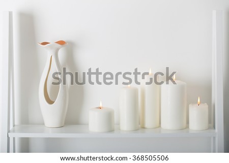 white candles burning on a white shelf