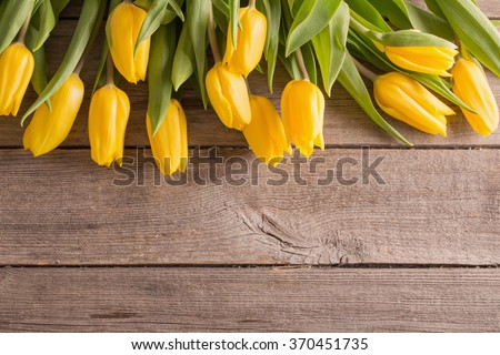 yellow tulips over wooden table background